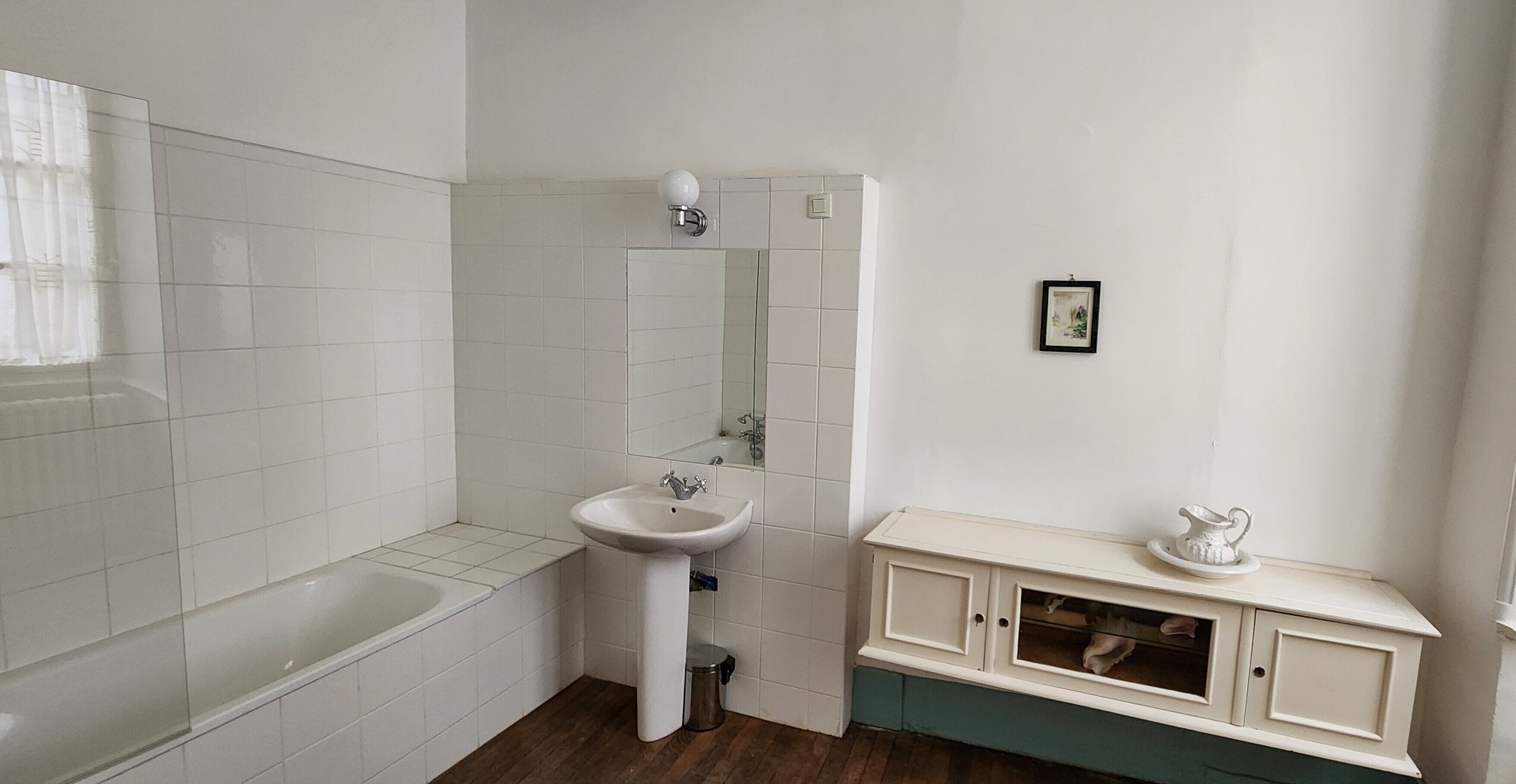 A bathroom with a bathtub, a sink, and a vanity with a mirror.