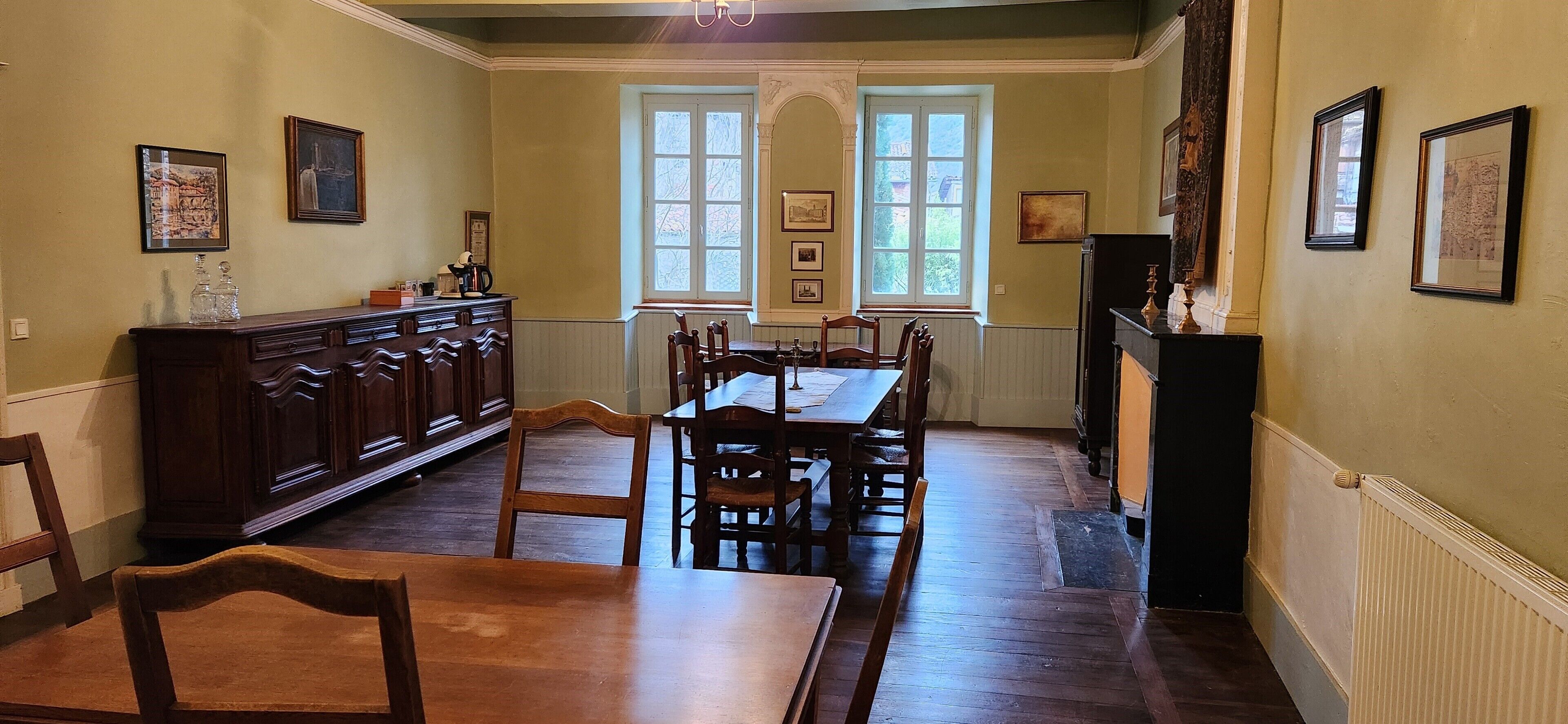 A dining room with a wooden table and chairs, a cabinet, and framed pictures on the walls.