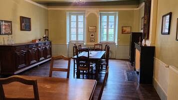 A dining room with a wooden table and chairs, a cabinet, and framed pictures on the walls.