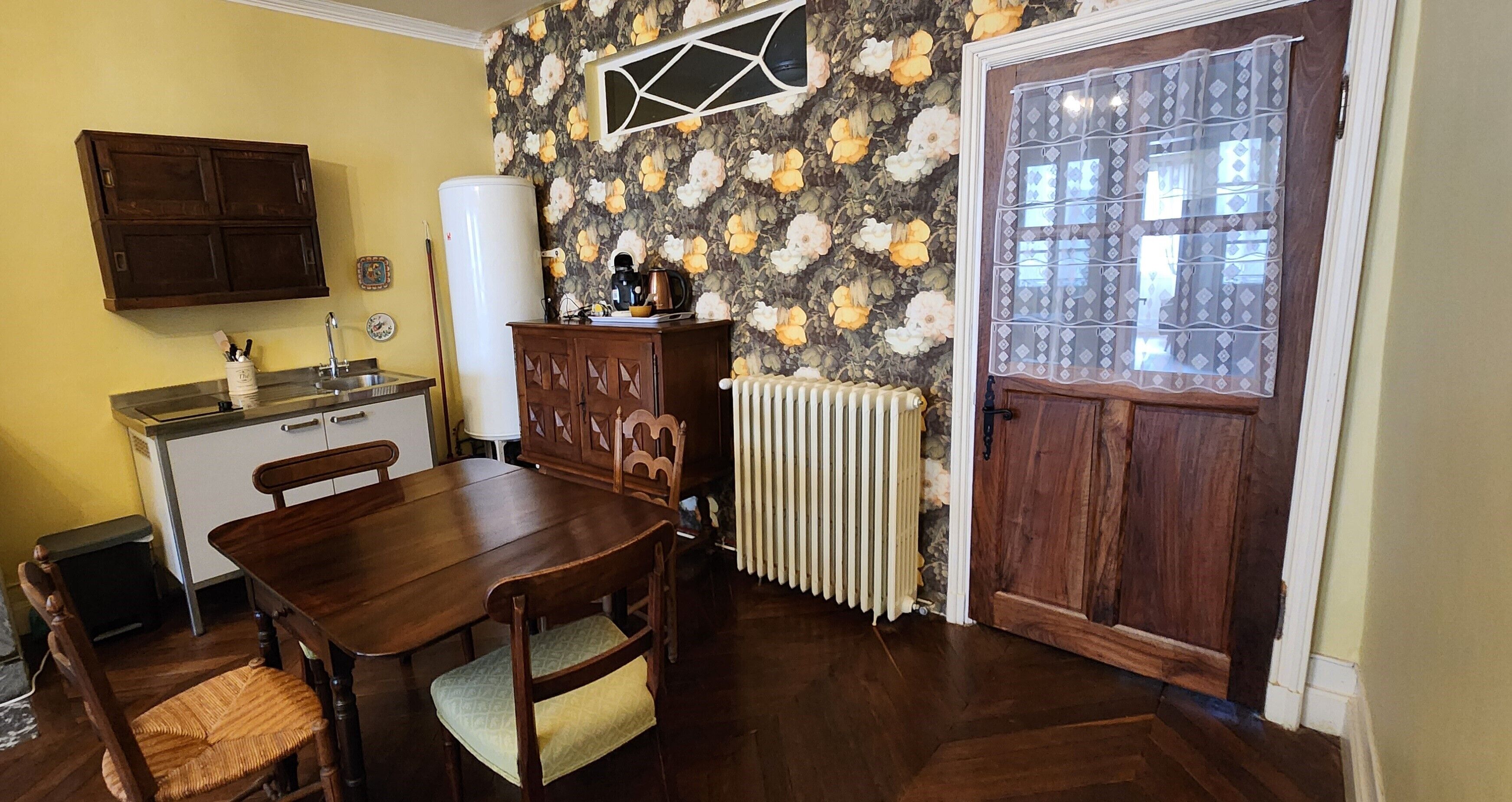 A dining area with a wooden table and chairs, a radiator, a water heater, and a cabinet.