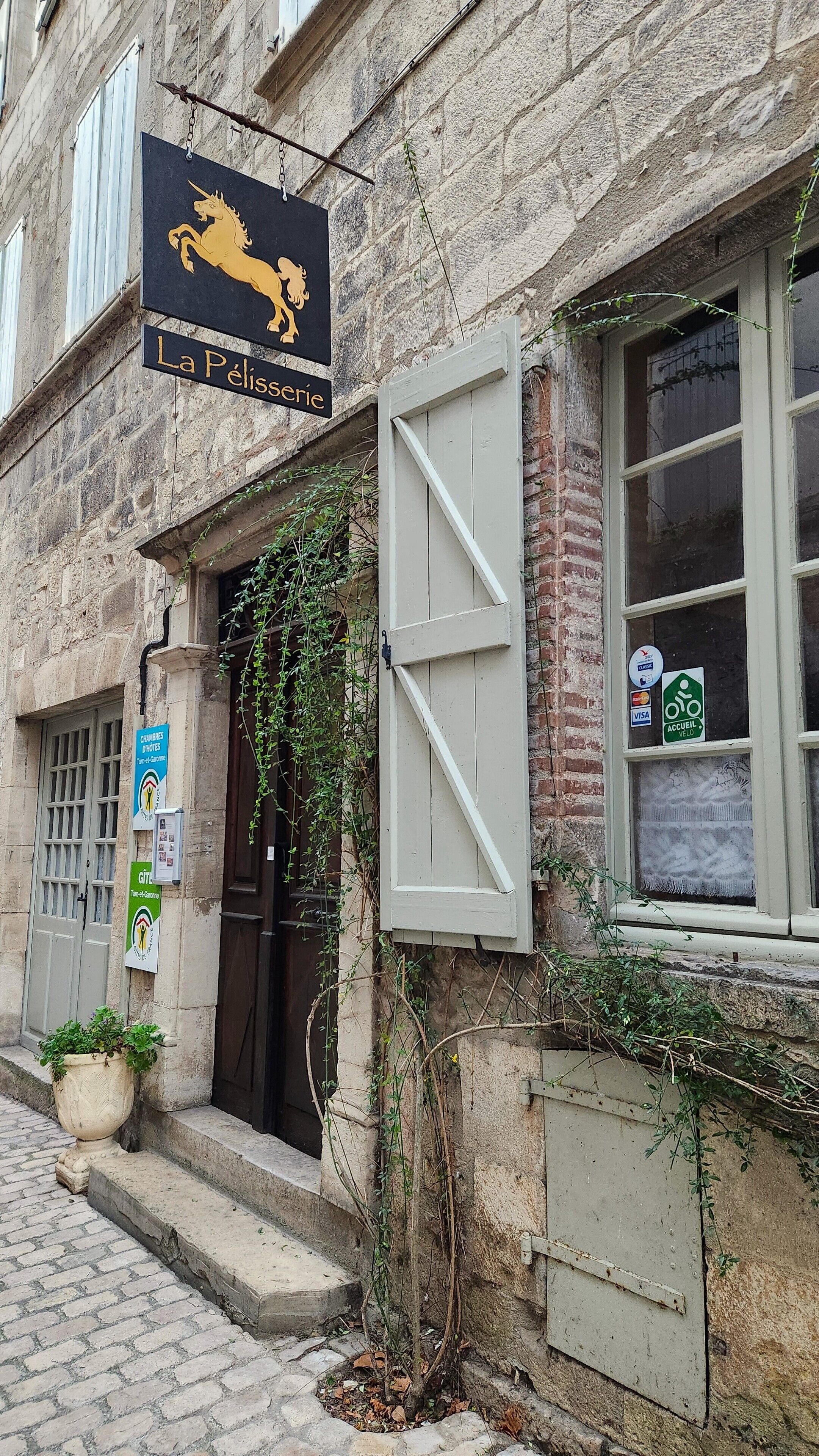 A building with a sign reading "La Pelisserie" and a horse symbol. There are signs for "Chambres D'Horloge" and "Accueil Vélocité."