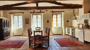 Una cocina rústica con vigas de madera a la vista, una mesa de comedor con sillas y una alfombra roja en el suelo.