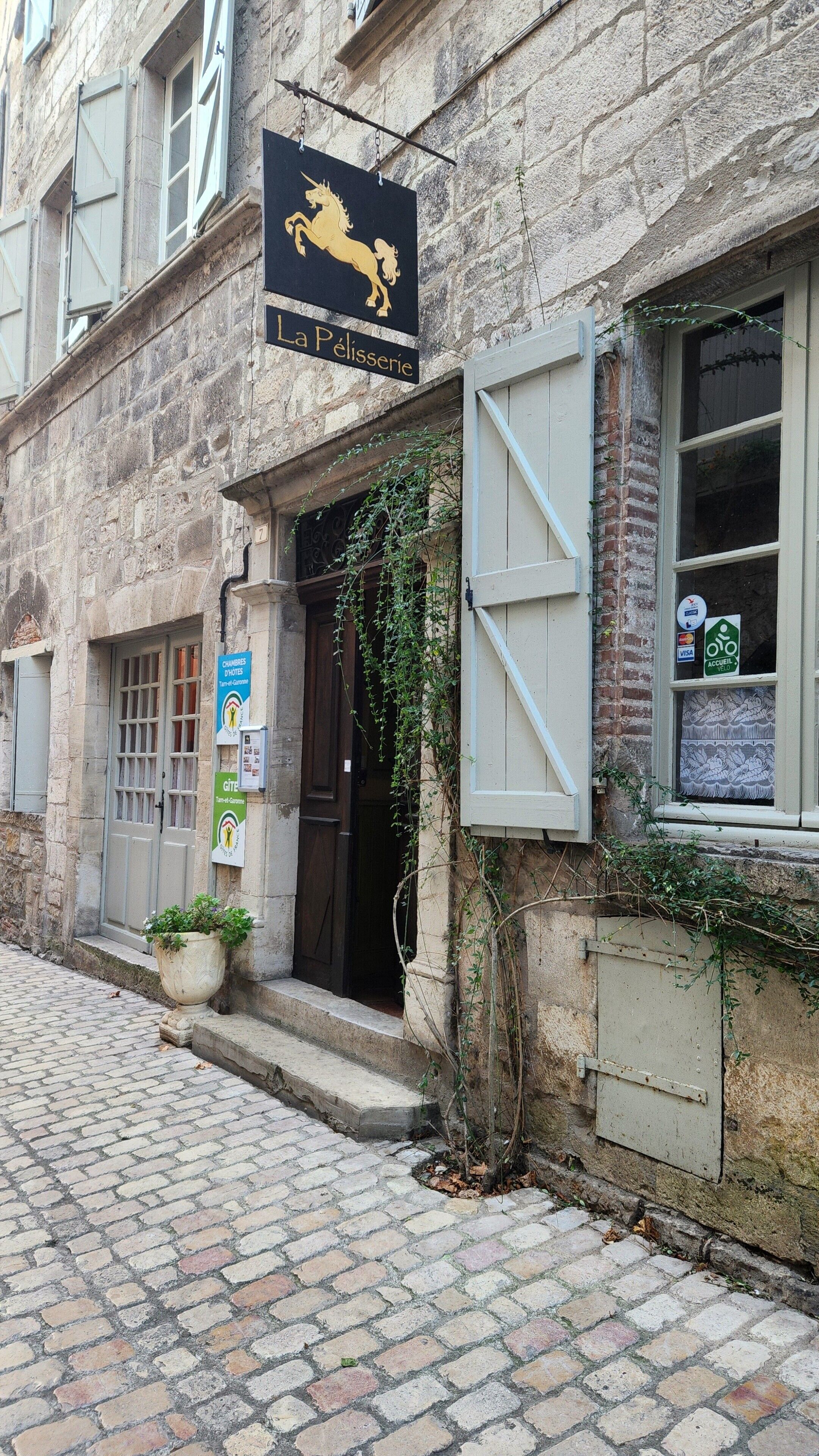 A stone building with a black sign reading "La Pélisserie".