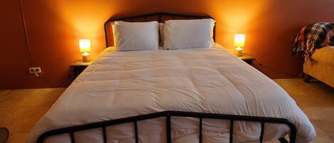 A neatly made bed with white linens, two bedside lamps, and a wooden nightstand.