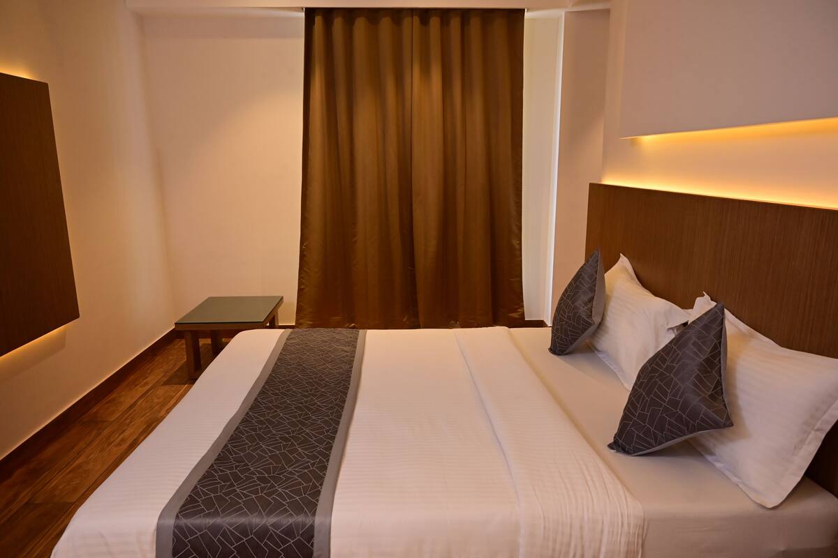 Une chambre d’hôtel avec un lit, une petite table et un rideau.