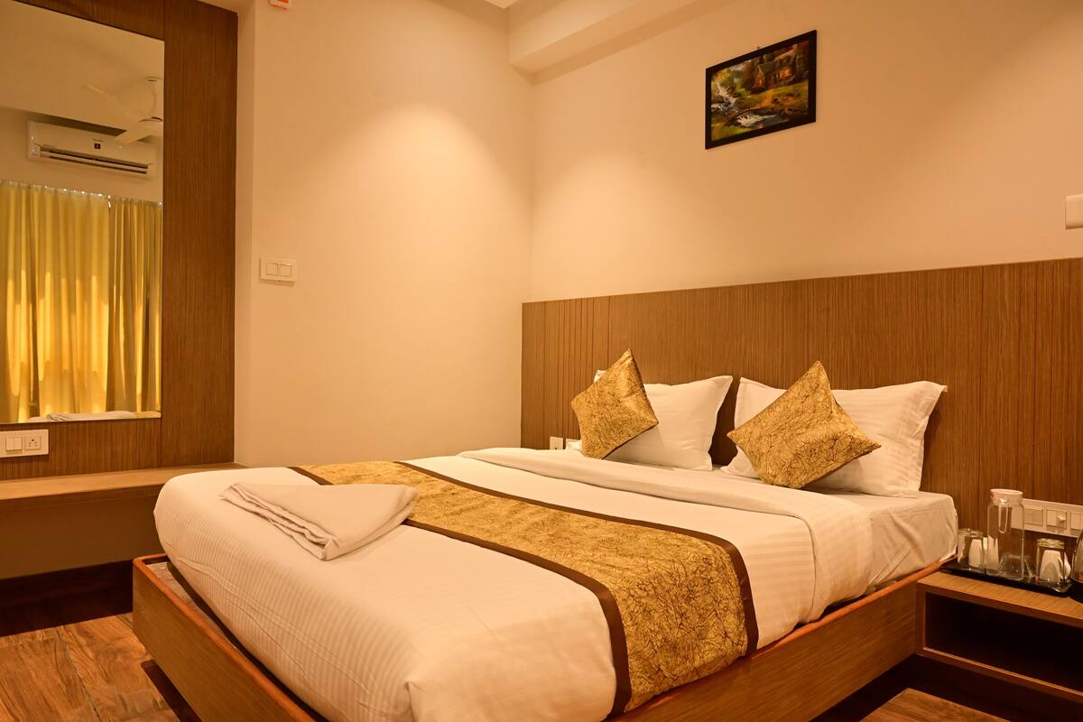 Une chambre d’hôtel avec un grand lit, une tête de lit en bois et un tableau accroché au mur.