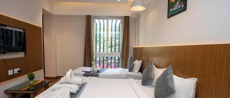 A hotel room with two beds, a television, a window with curtains, and a painting on the wall.