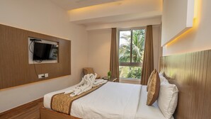 Una habitación de hotel moderna con una cama de madera, un televisor de pantalla plana montado en la pared, una ventana con cortinas y una pequeña planta en maceta.
