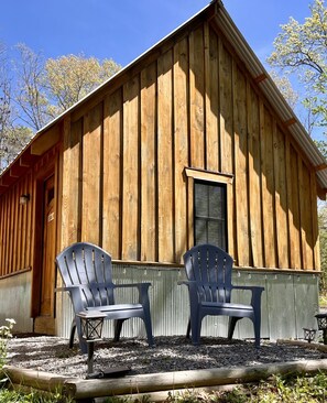 A wooden cabin with two Adirondack chairs outside.