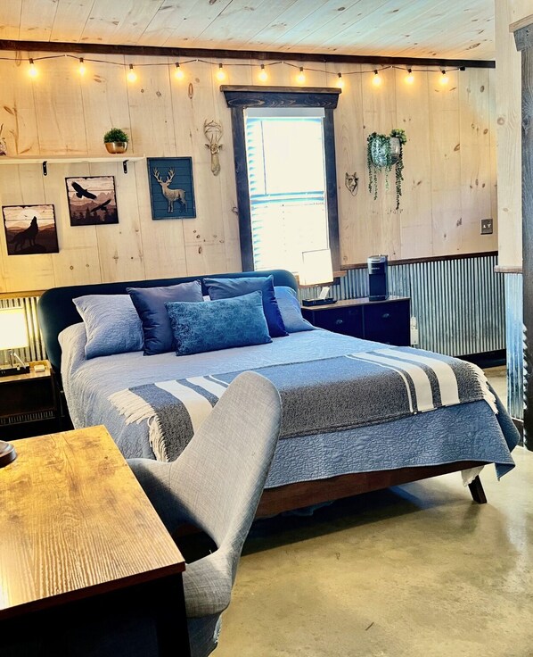 Quarto com cama, mesas de cabeceira, uma janela e decorações nas paredes.