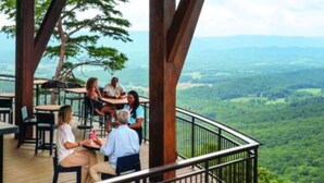 Une terrasse en bois avec des sièges extérieurs, offrant une vue sur un paysage boisé.