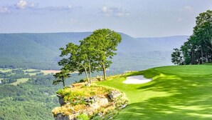 Un parcours de golf offrant une vue dégagée sur le paysage environnant, notamment les arbres et les collines au loin.