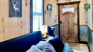 Une pièce chaleureuse avec un canapé bleu, une porte en bois et une décoration murale représentant une tête de cerf.