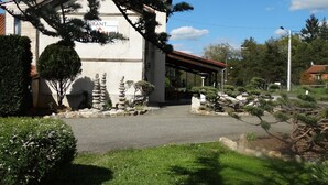 Un bâtiment portant une enseigne indiquant qu’il s’agit d’un restaurant, entouré d’un aménagement paysager soigné comprenant des rochers, des arbustes et des arbres.