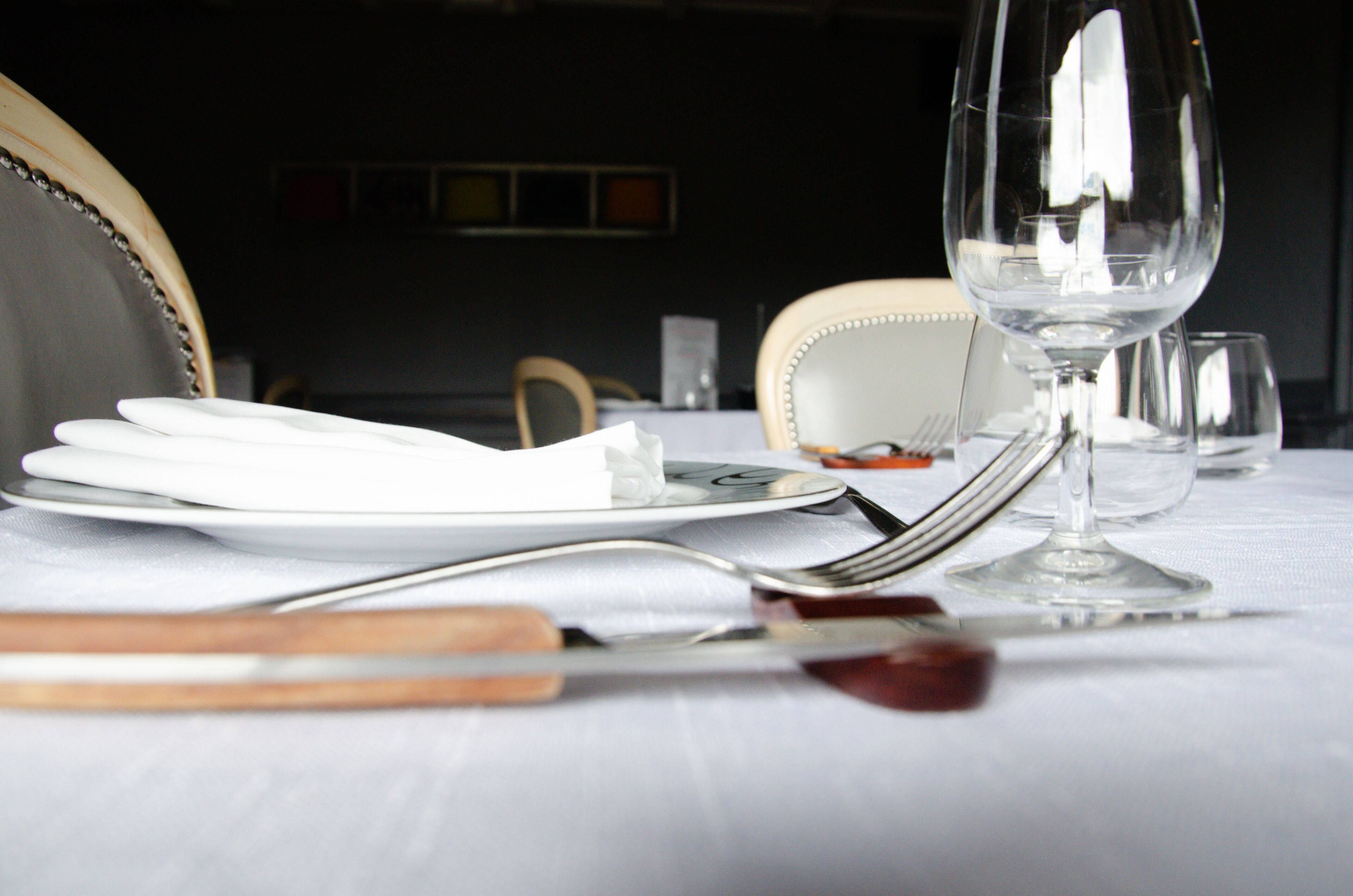 Une table mise pour le repas, avec des assiettes, des couverts et un verre à vin.