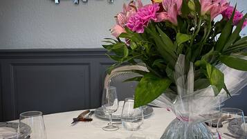 Een tafel gedekt met een vaas roze bloemen, glazen en een zwarte asbak.