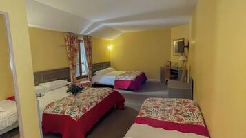 A hotel room with two beds, a mirror, a nightstand, and a window with curtains.