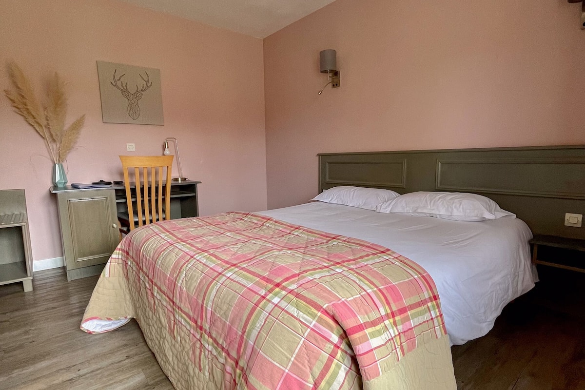 Une chambre à coucher comprenant un lit, un bureau, une chaise et une lampe fixée au mur.
