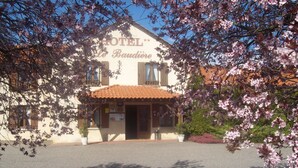 Un hôtel appelé « HÔTEL Le Baudire », doté d’une façade traditionnelle, d’un toit recouvert de tuiles et d’une enseigne.