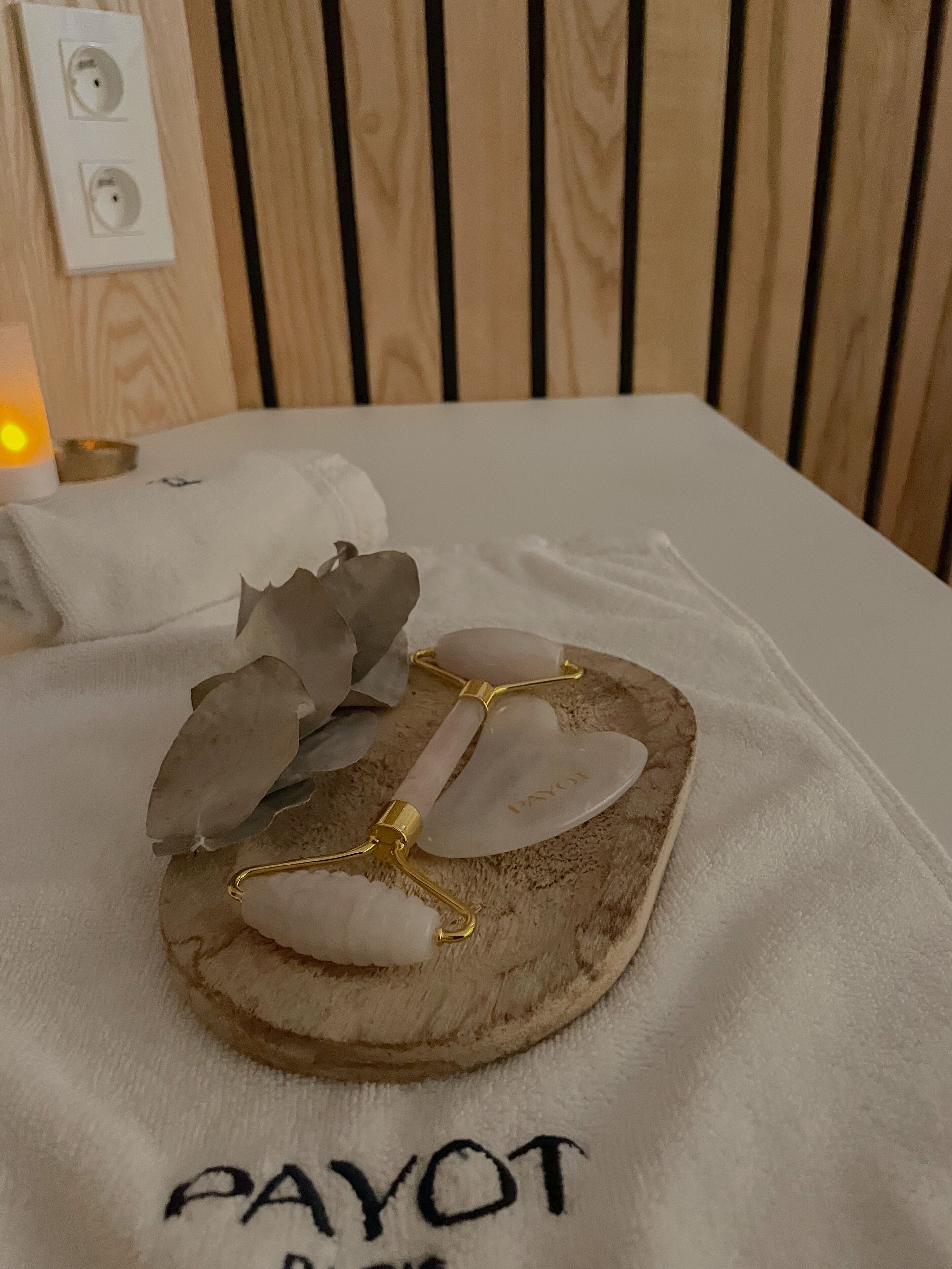 Ein Bett mit einem weißen Handtuch und einem dekorativen Holztablett mit der Aufschrift "PAYOT".