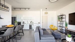 A modern living space with a dining area, sofa, and a kitchen in the background. - HaCarmel Market Vibrat Apt by Sea N Rent (Tel Aviv)