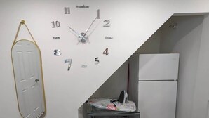 A room with a wall-mounted clock, a door, and a refrigerator. - Stylish Studio, Steps to Transit (Montréal)