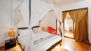 A bedroom with a four-poster bed, a ceiling fan, a nightstand with a lamp, and a view of the outside through a glass door. - Verandah Goa (Anjuna)