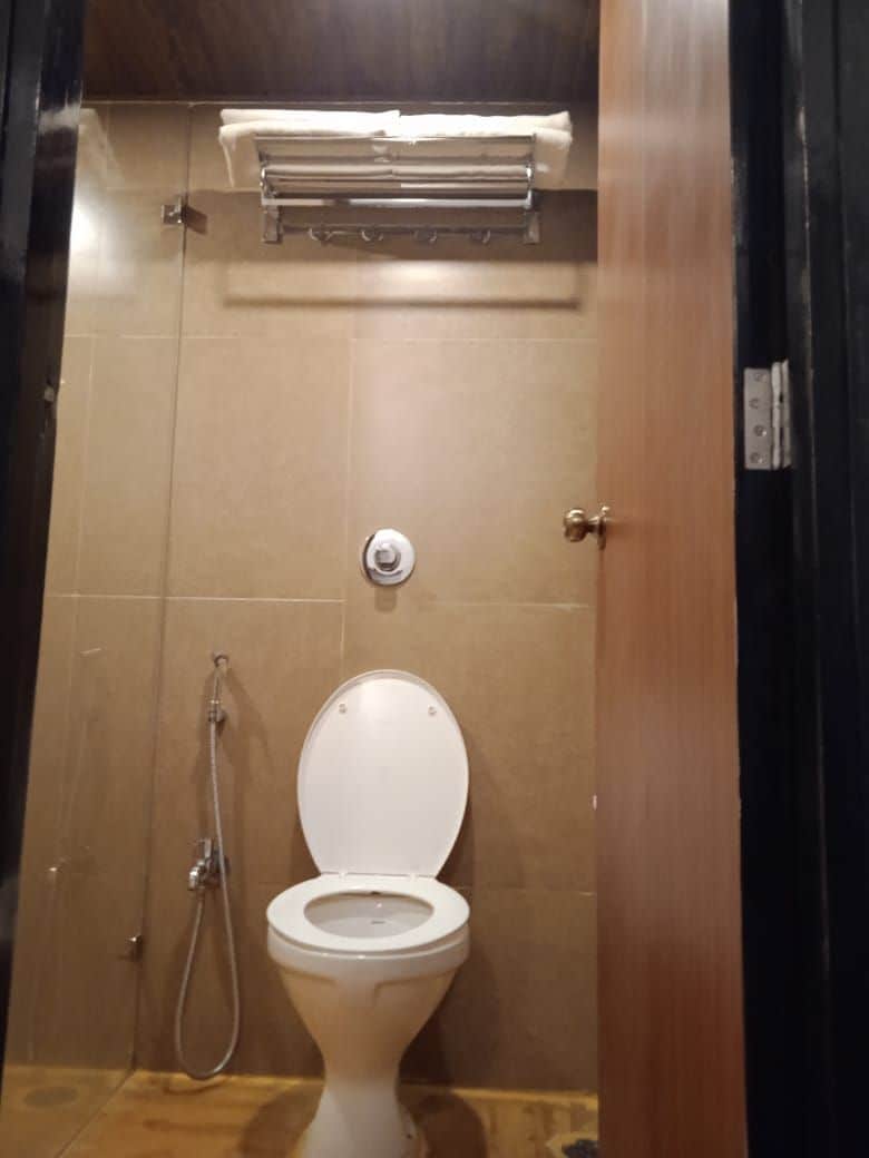 Un baño con inodoro, ducha y toallero.