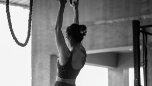 A person performing an exercise on gymnastic rings in a gym with a concrete floor and metal equipment. - Verandah Goa (Anjuna)