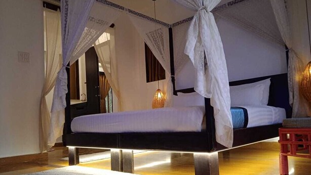 A bed with a canopy, a bedside table, and a rug. - Verandah Goa (Anjuna)