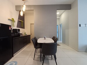 A modern kitchen with a dining area, featuring a black refrigerator, a coffee machine, and a round table with four chairs. - The Horizon Ipoh 2BR L11 by Grab A Stay (Ipoh)