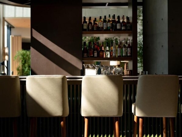 Un coin bar avec trois chaises et une étagère remplie de différentes bouteilles.