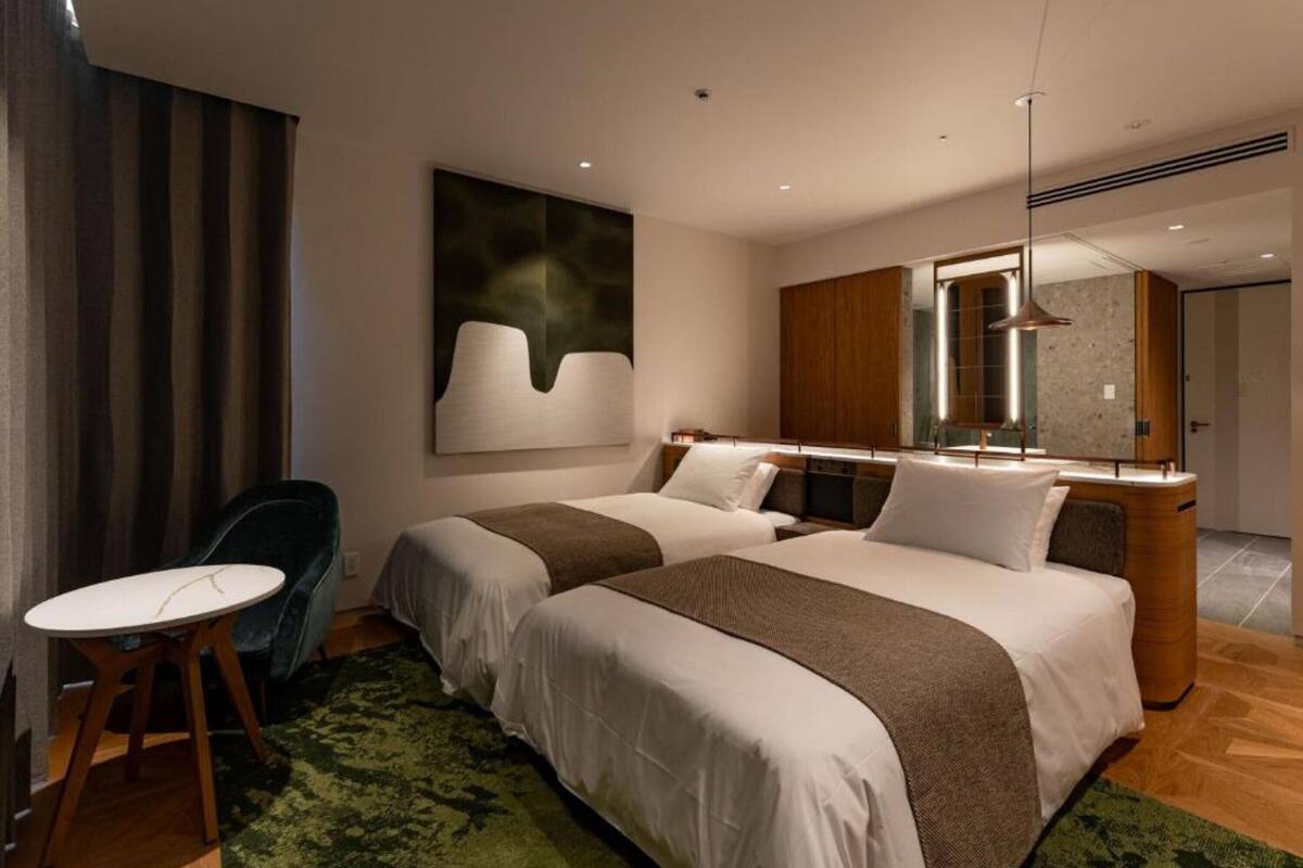 A modern hotel room with two beds, a desk, and a large mirror.