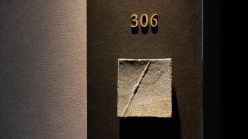 Paret fosca i amb textura, amb el número '306' i una placa de pedra.