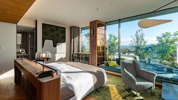 A modern bedroom with a large bed, a desk, a chair, and a view of the outdoors.