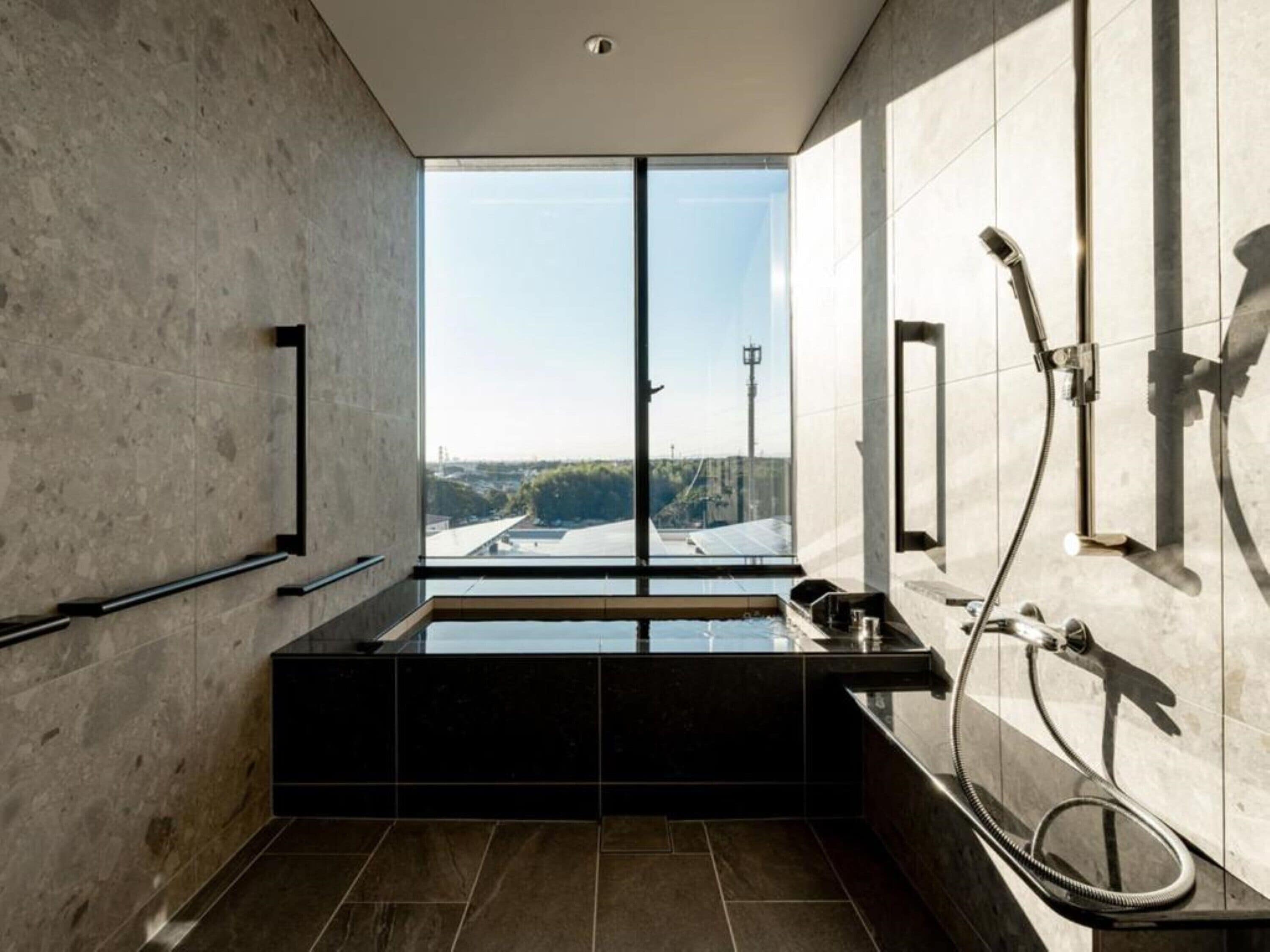 A modern bathroom with a large window, a bathtub, and a shower area.