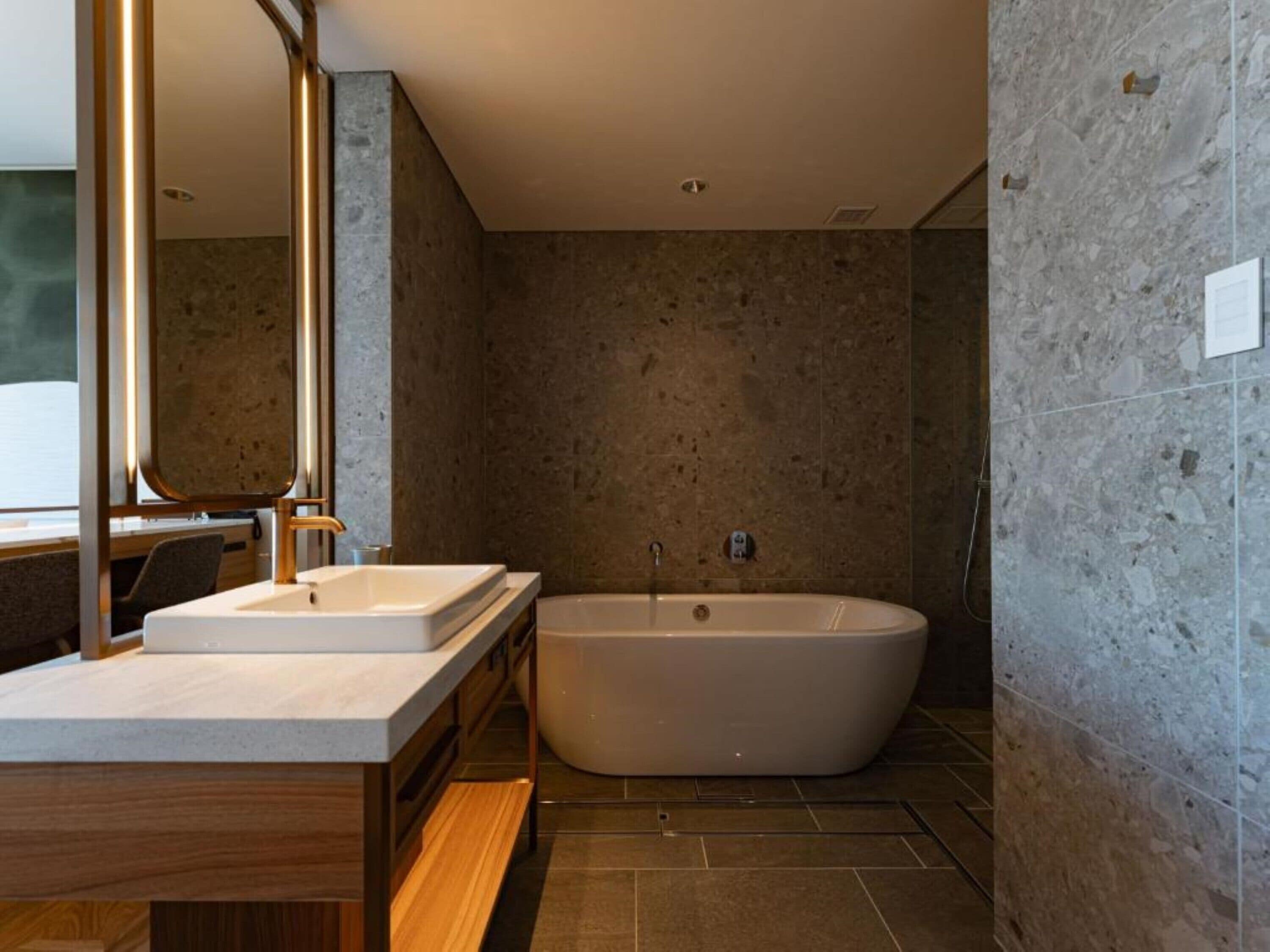Un baño moderno con una bañera independiente, un tocador doble y un espejo grande.