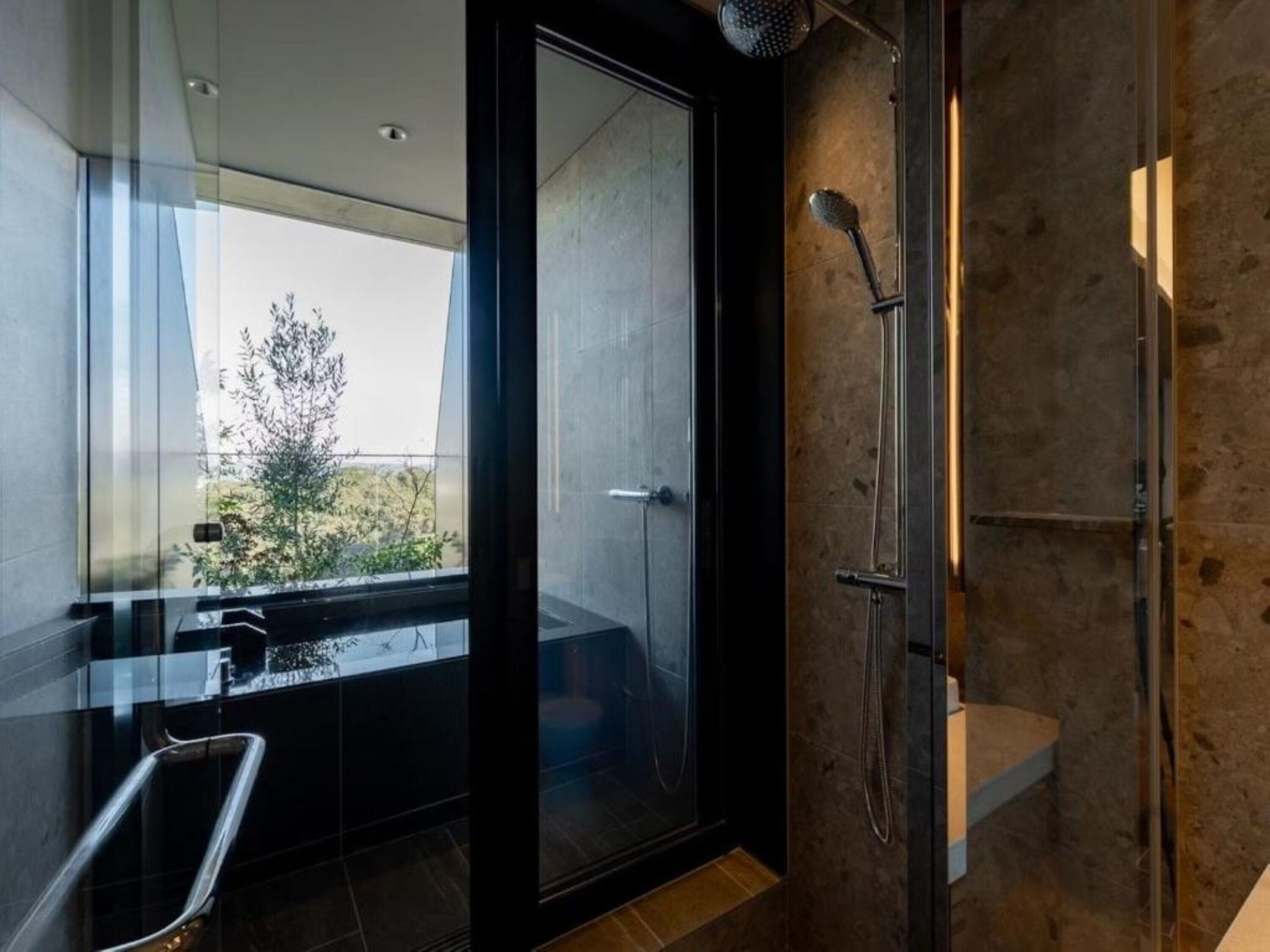 Ein modernes Badezimmer mit Duschkabine aus Glas, Blick ins Freie und integriertem Waschbecken.