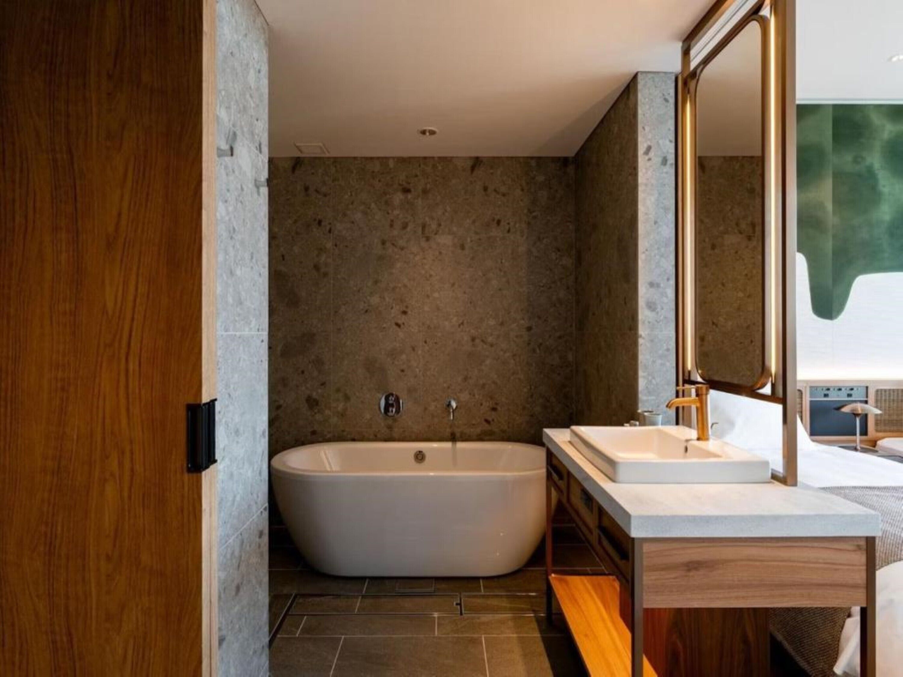 Un baño moderno con una bañera independiente, un tocador con espejo, y un espejo grande sobre el tocador.