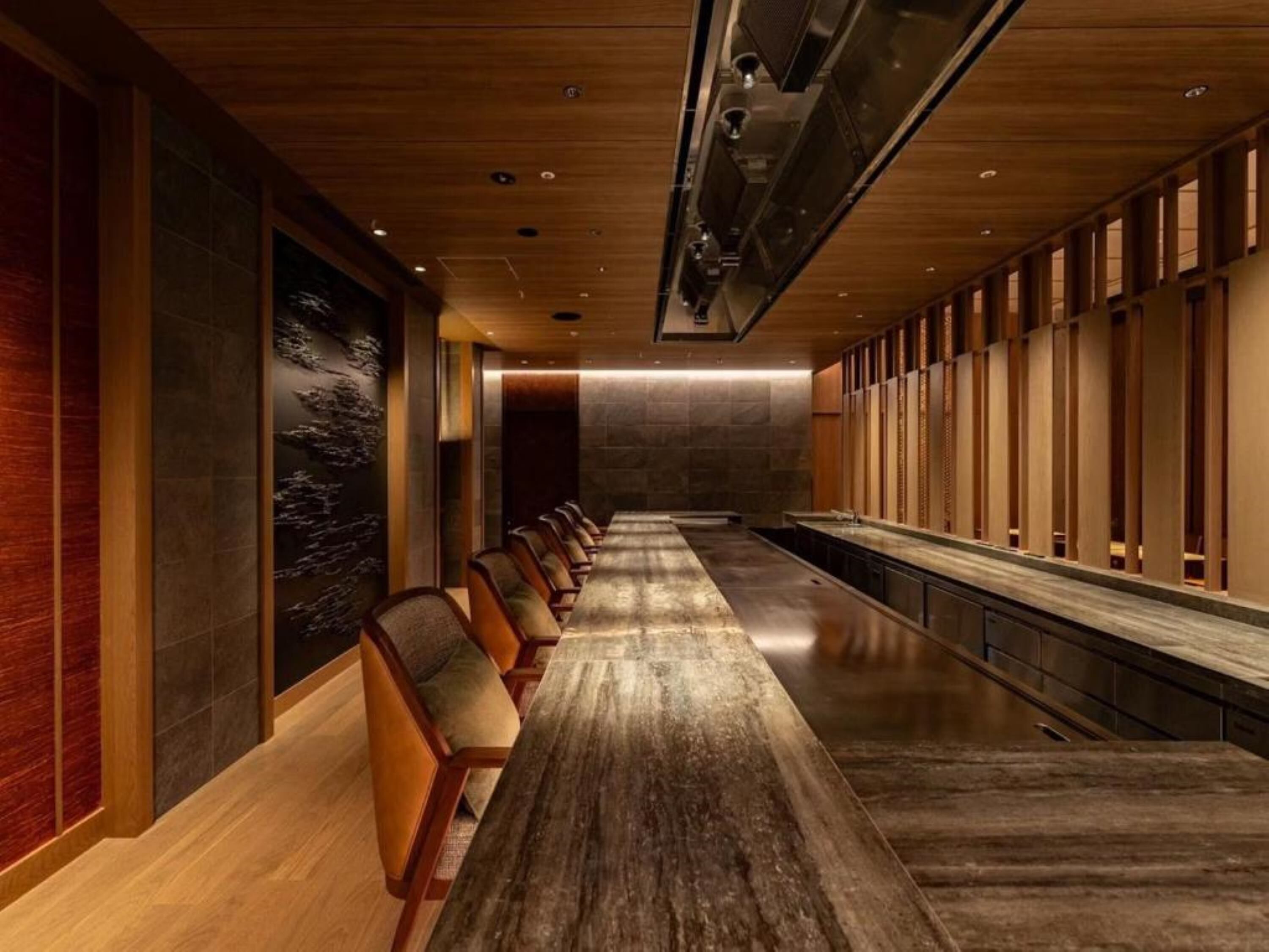 A long, narrow hotel lobby with a wooden floor, rows of chairs, and a long table.