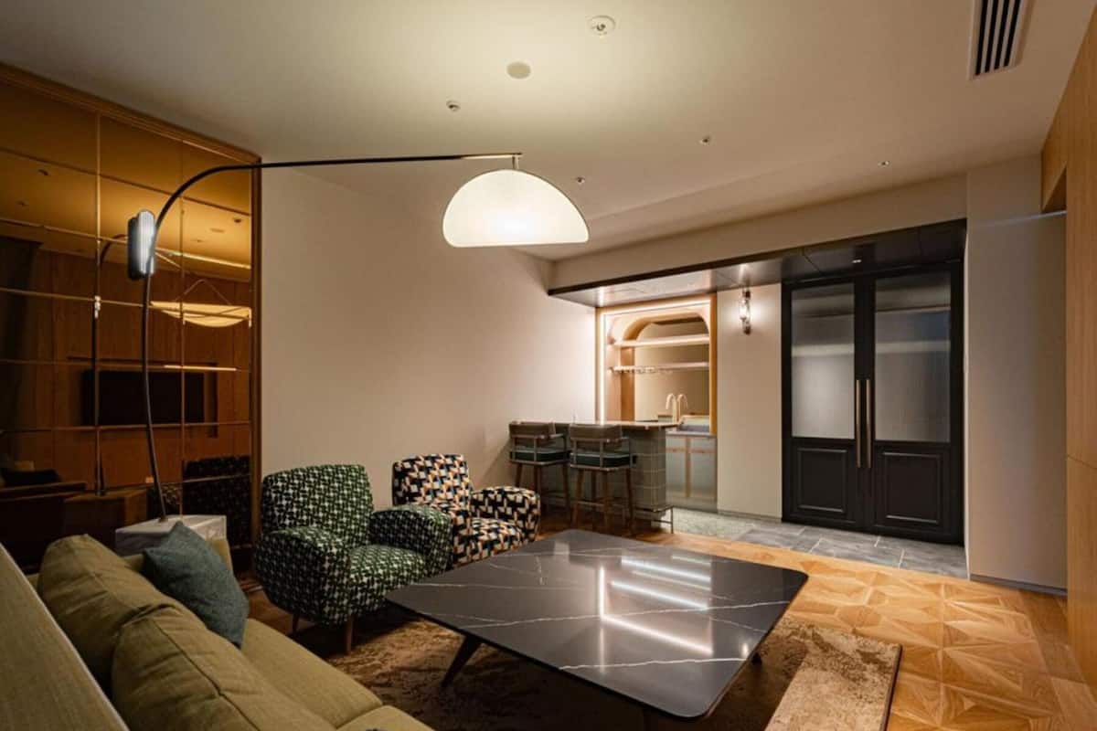 A modern living room with a sofa, patterned chairs, a coffee table, and a pendant light.