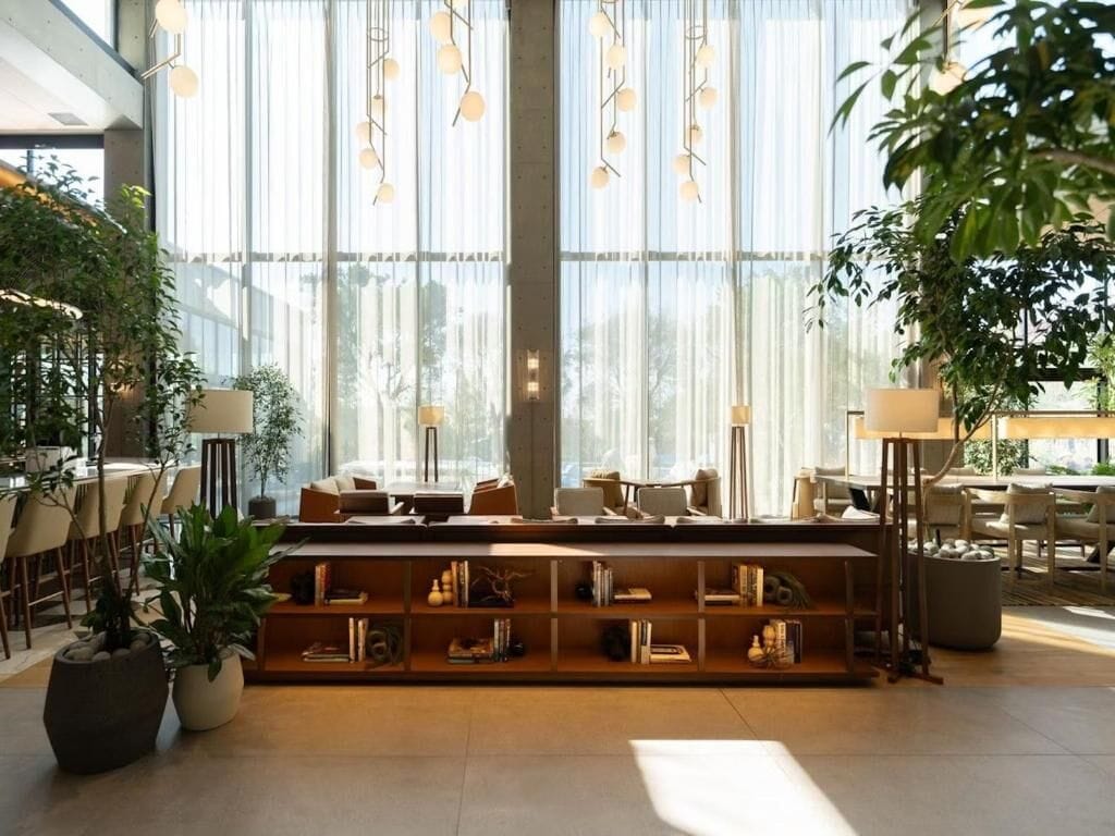 Um interior moderno com área de estar central, janelas amplas e plantas de interior.