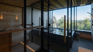 Un interior moderno con paredes de vidrio, vigas de madera y vistas a la vegetación.