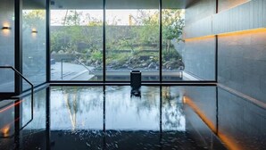 Un área de piscina interior moderna con amplios ventanales, vistas despejadas al exterior y un diseño elegante y minimalista.