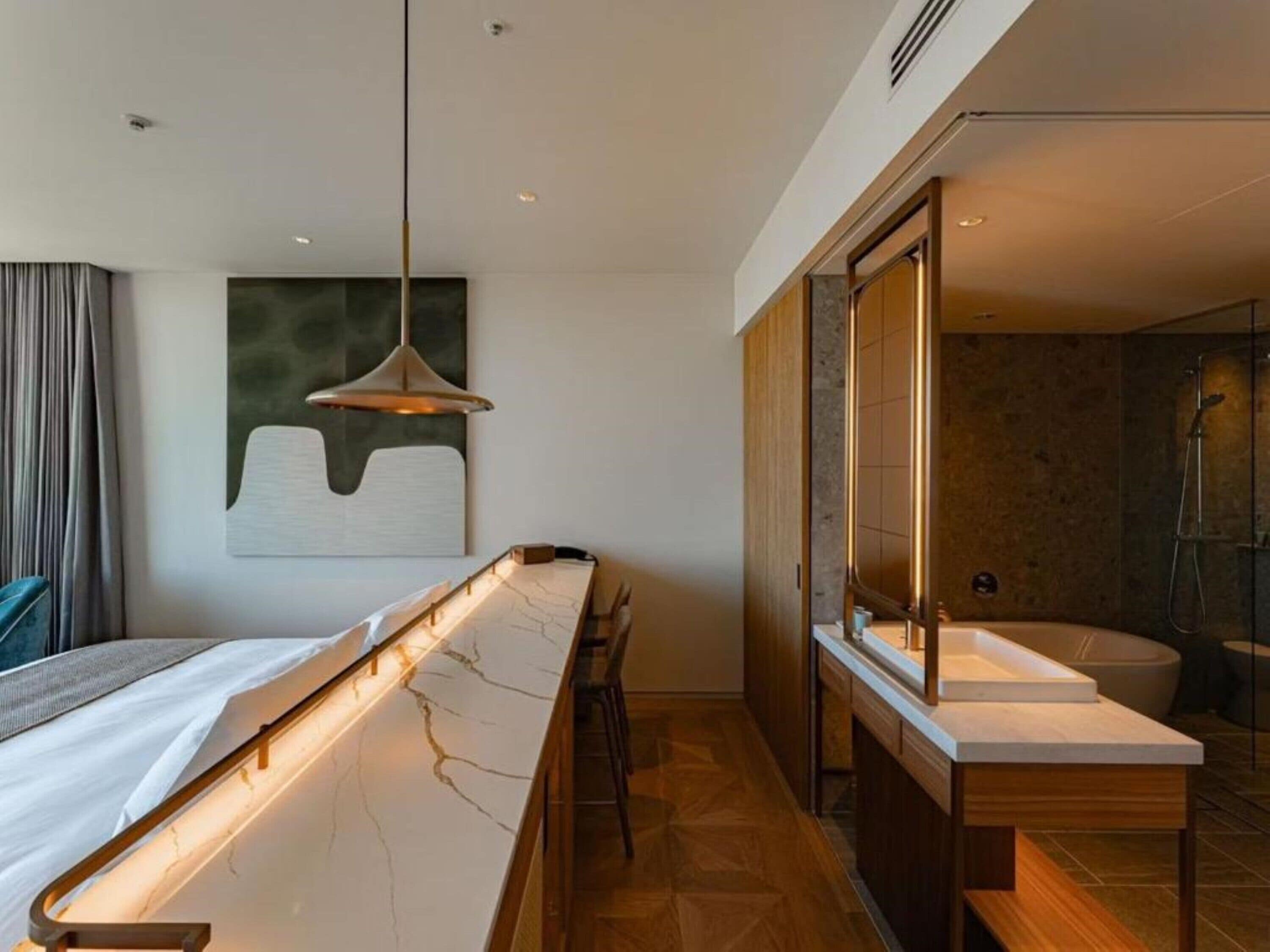 A modern bathroom with a large mirror, a bathtub, and a vanity with a sink.