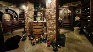 A dimly lit room with stone pillars, a wooden barrel, and shelves filled with bottles. - Cozy Accomodation Retreat (Quarten)