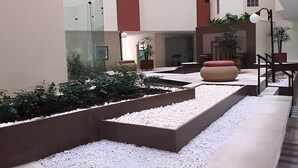 En modern innergård med en minimalistisk design, som har en central sittgrupp, en glasvägg och en krukväxt.