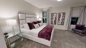 A modern bedroom with a large bed, bedside tables, a glass coffee table, and artwork on the walls. - Luxury 6B Pool Home At Storey Lake (Kissimmee)