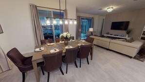 A modern living room with a dining area, a sofa set, a flat-screen TV, and a large window with curtains. - Luxury 6B Pool Home At Storey Lake (Kissimmee)