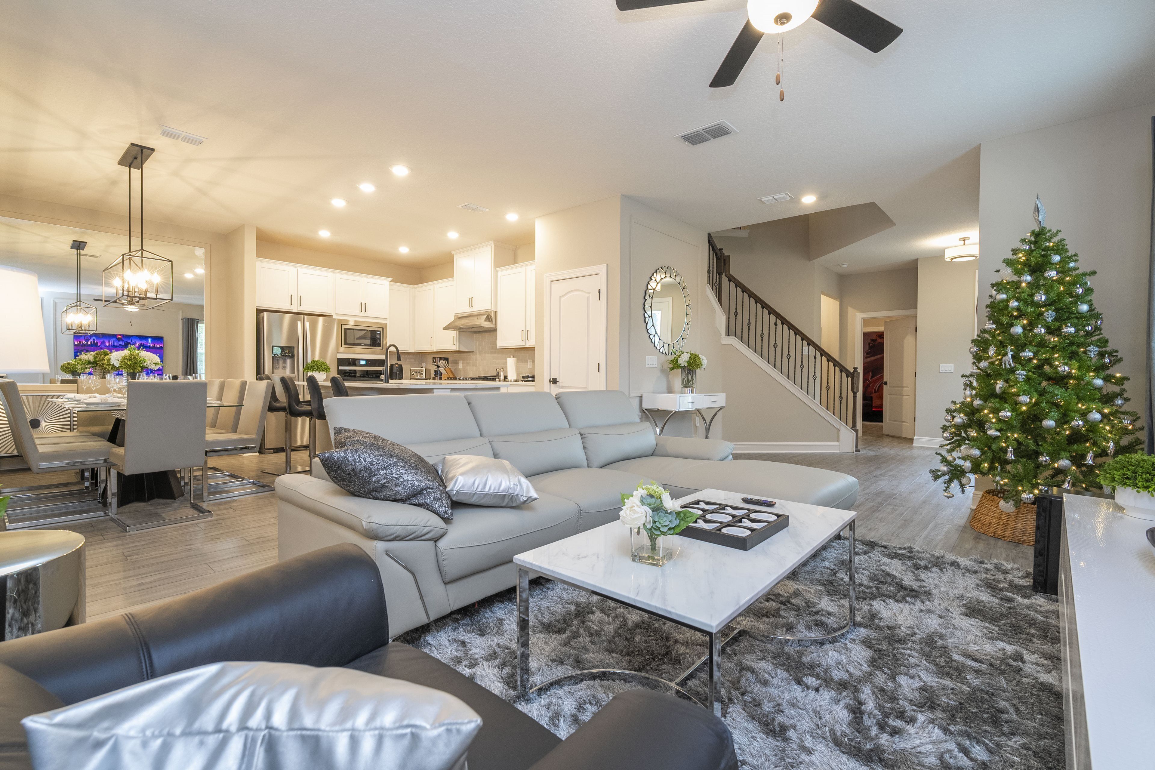 A modern living room with a gray sofa, a coffee table, and a Christmas tree.